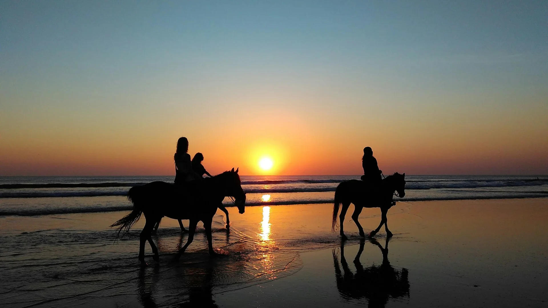 Reiter auf Pferden am Strand im Sonnenuntergang – stimmungsvolles Küstenmotiv für eine Reitsafari in Afrika