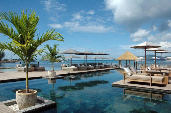 Pool und Liegebereich des Le Domaine de L'Orangeraie mit Palmen und Meerblick auf La Digue, Seychellen