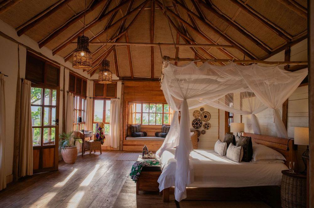 Himmelbett mit weißem Moskitonetz in der Kyambura Gorge Lodge, Uganda