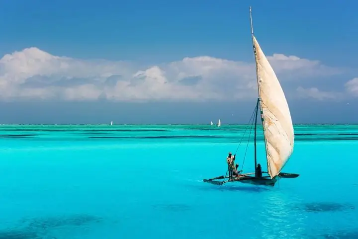 Traditionelle Dhow mit Segel vor Sansibar in Tansania im Abendlicht des Indischen Ozeans