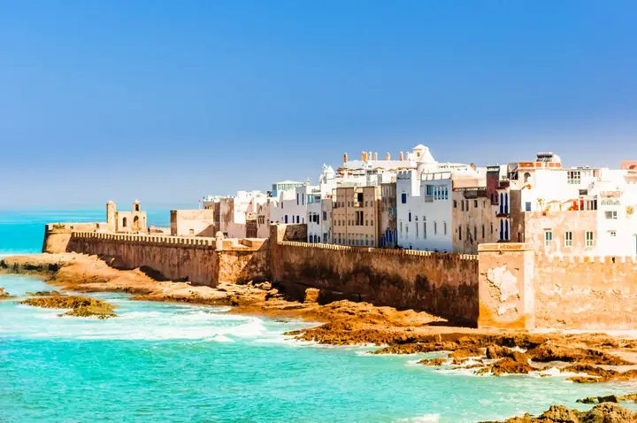 Weiß-blaue Altstadt von Essaouira in Marokko hinter der Stadtmauer am türkisfarbenen Atlantik