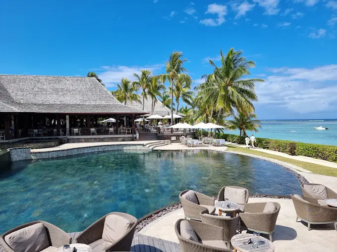Pool und Strandbar des Lux* Le Morne auf Mauritius mit türkisfarbener Lagune und Palmen