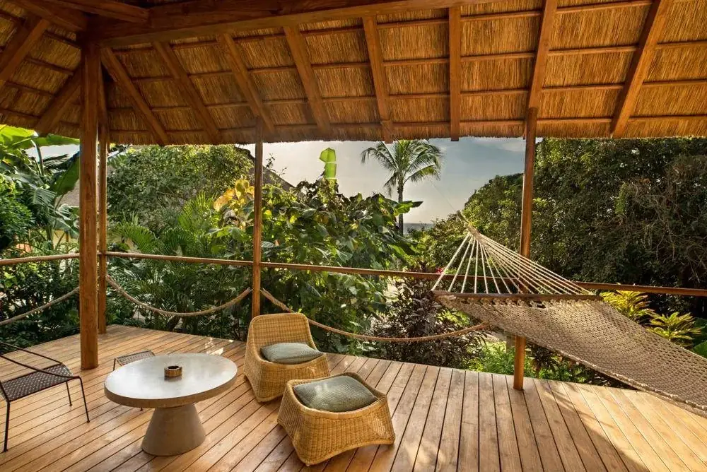 Holzterrasse des Zuri Zanzibar Resorts in Tansania mit Hängematte und Blick auf tropischen Garten
