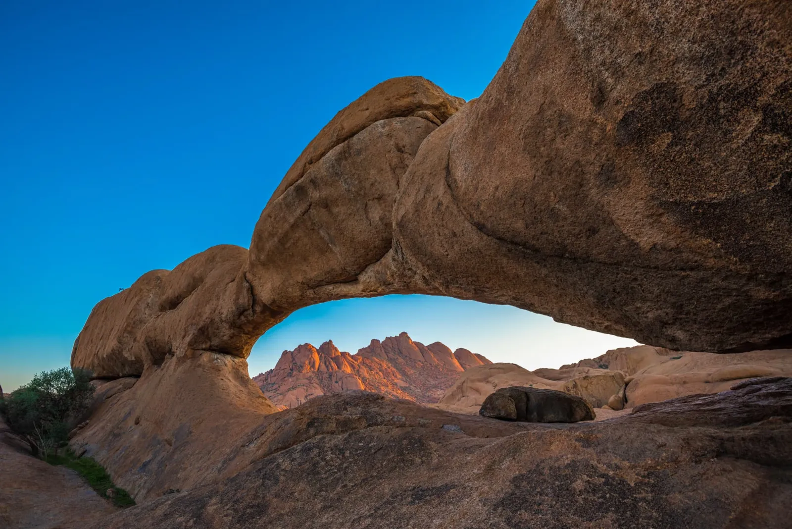 Granitbogen der Spitzkoppe im Damaraland in Namibia mit rot leuchtenden Felsgipfeln im Abendlicht